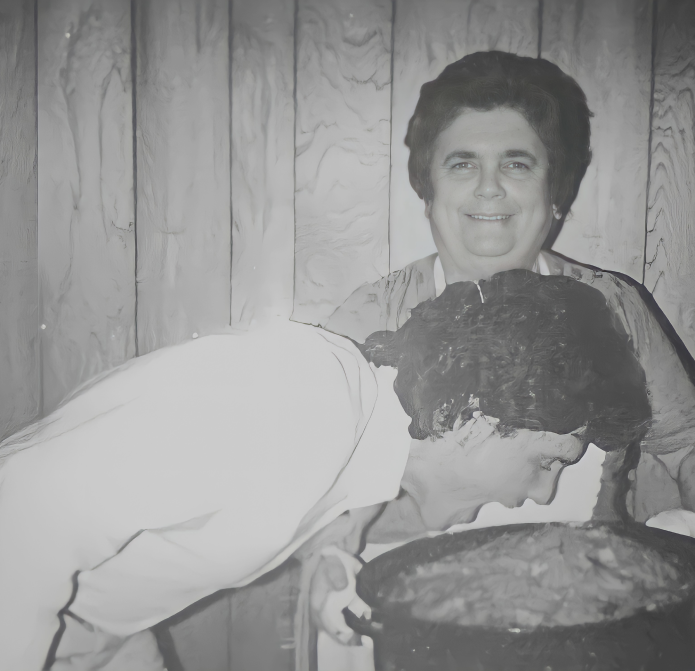 A man bends over, playfully pretending to eat the delicious contents of a pot held by another woman