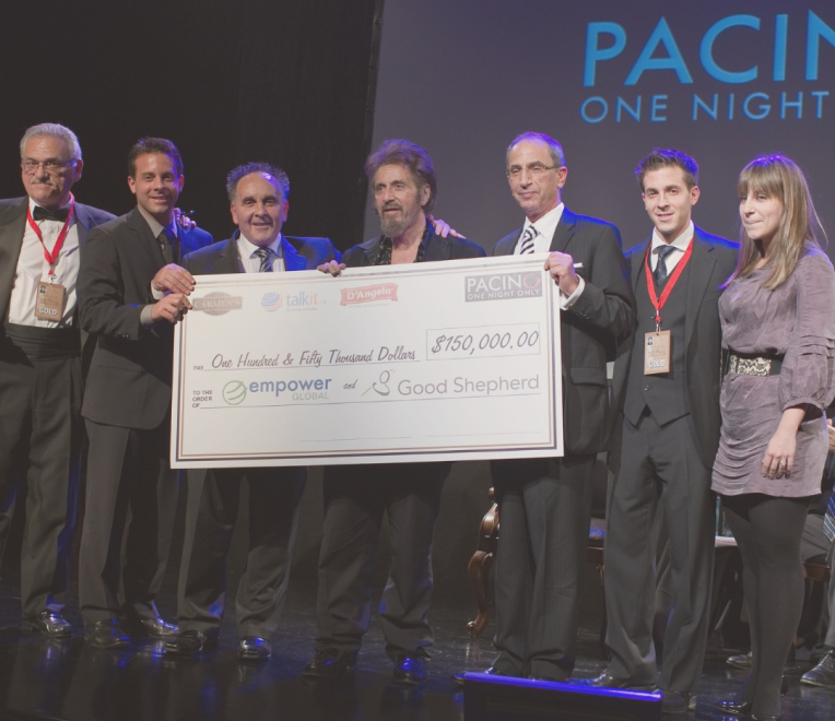 A group of individuals stands proudly on a stage, holding a large cheque with the amount of $150,000 prominently displayed